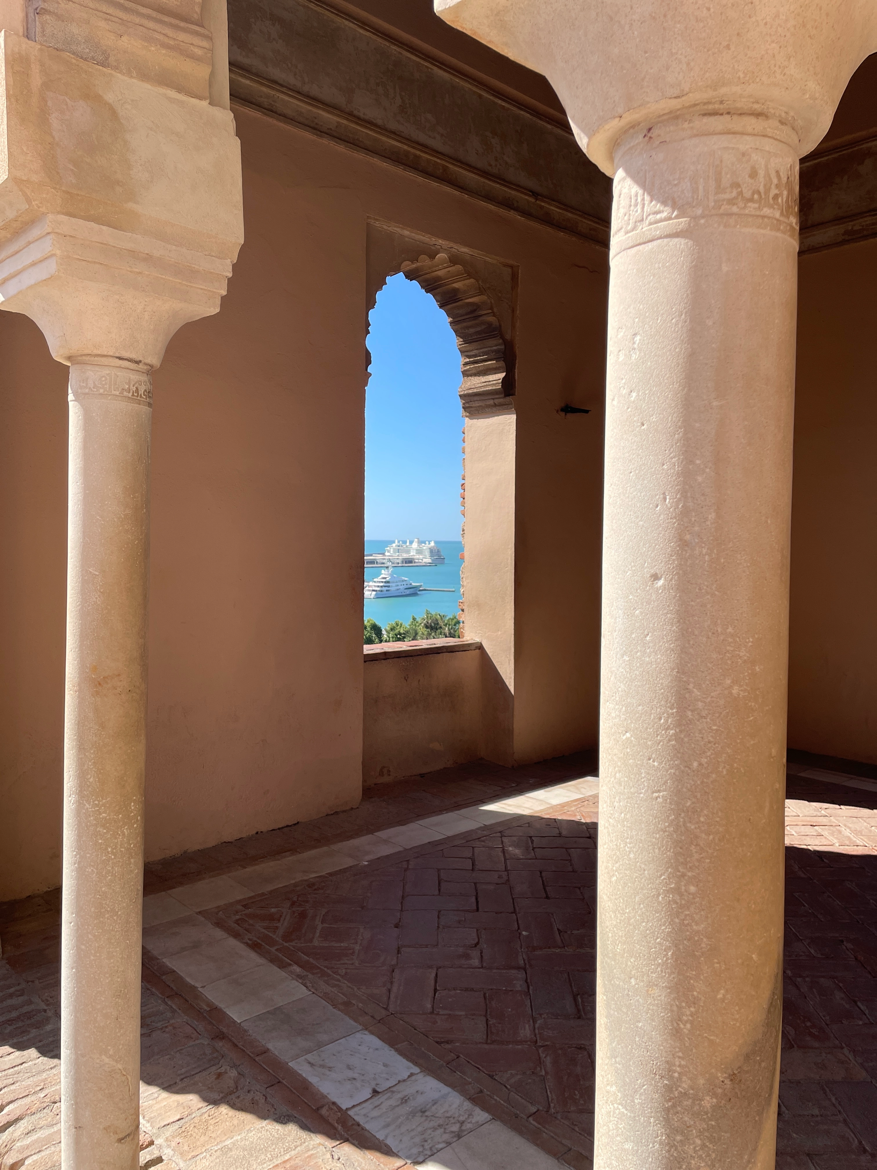Blick durch maurische Bögen auf das Meer und Schiffe